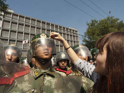 9月15日,日本驻华使馆前,一个女孩儿为武警擦去头盔上的鸡蛋残液